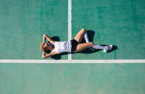 Mujer bonita en el campo de fútbol descansando en el suelo
 - Foto, imagen