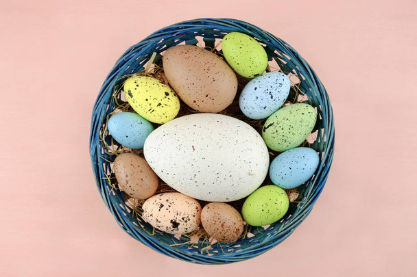 Easter colorful quail eggs in blue basket on a pale pink background.  - Photo, Image
