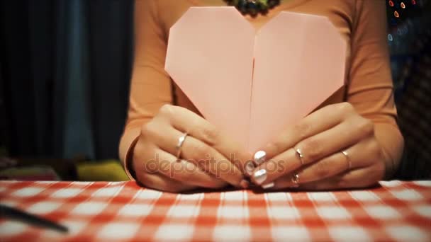Mujer mostrando corazón de origami de papel rosa a cámara
 - Metraje, vídeo