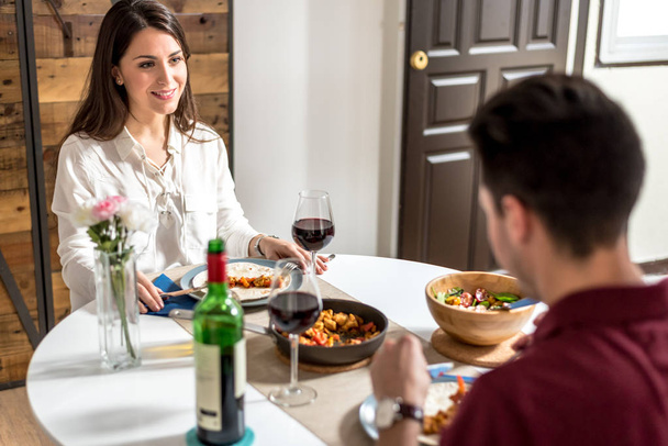 Happy young couple eating and drinking wine at home  - Foto, Bild