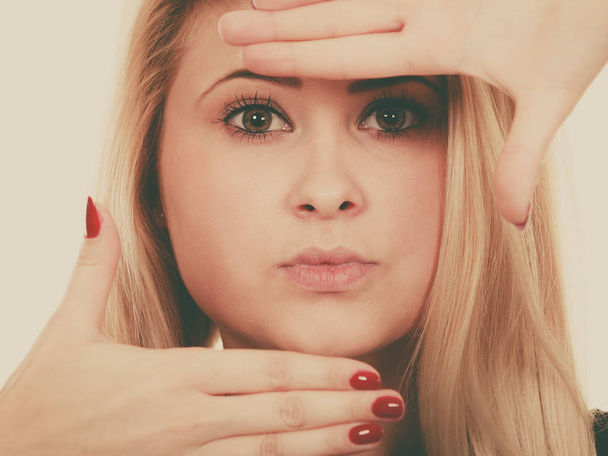 Portret van blonde vrouw met handen dicht bij gezicht - Foto, afbeelding