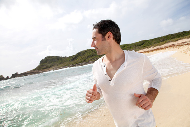 Man running on a sandy beach - Fotó, kép