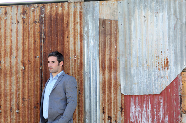 Businessman standing in front of sheet metal wall - Fotografie, Obrázek