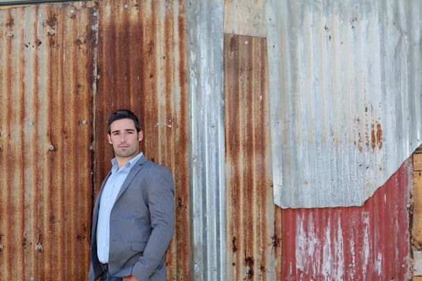 Businessman standing in front of sheet metal wall - Foto, Imagen