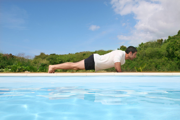 Man doing exercises by the pool - Foto, Bild