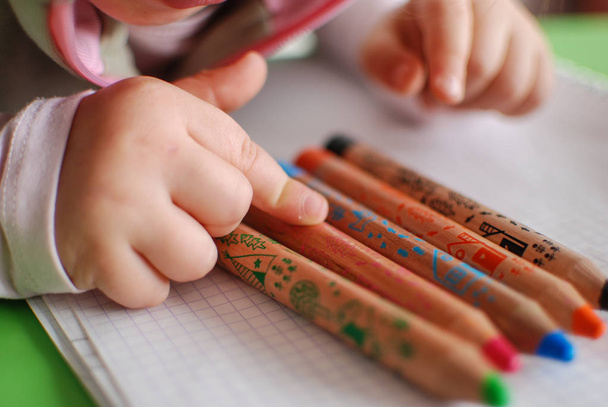 Child hand choosing between coloring pencils  - 写真・画像
