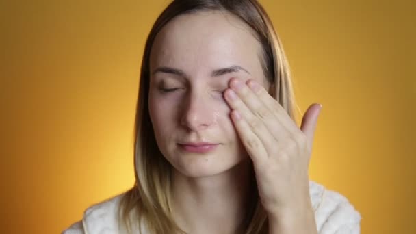 Woman cleaning face on a yellow background - Imágenes, Vídeo