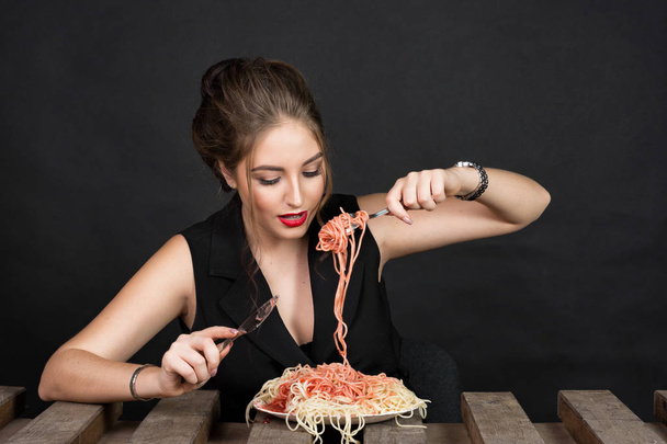 Woman eating pasta at wooden table - Фото, изображение