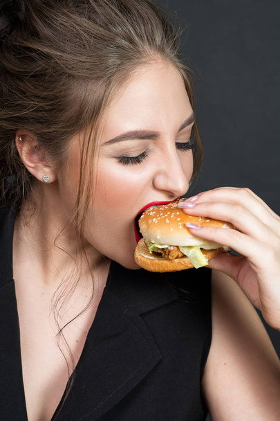 Slim beautiful woman eating a hamburger - 写真・画像