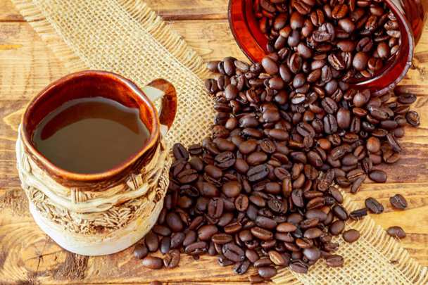 Tasse schwarzen Kaffee und Bohnen auf Holzgrund. - Foto, Bild