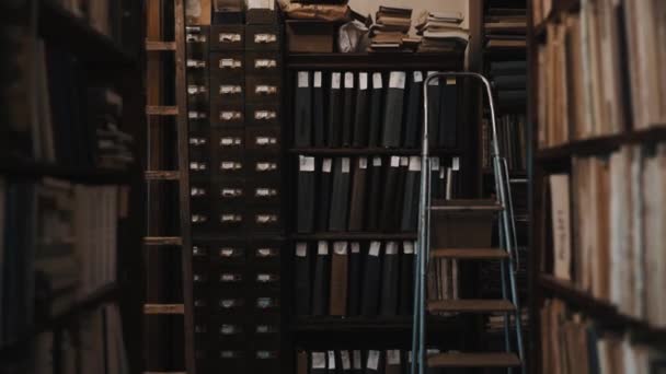 Dolly shot interior of old library bookshelves with document folders - Footage, Video