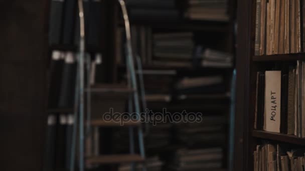 Dolly shot interior of old archive bookshelves with soft cover books - Footage, Video