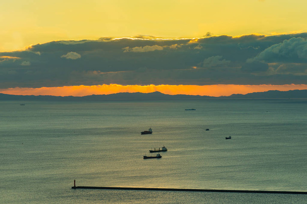Sonnenuntergang über der Küste mit Transportschiff im Ozean - Foto, Bild
