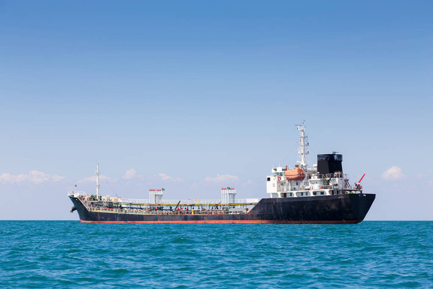 Buque de carga de petróleo en el horizonte oceánico con cielo azul claro
 - Foto, imagen