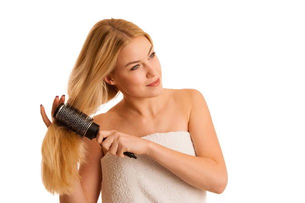 Beautiful blonde woman brushing her hair as a sign og hair care - Foto, afbeelding