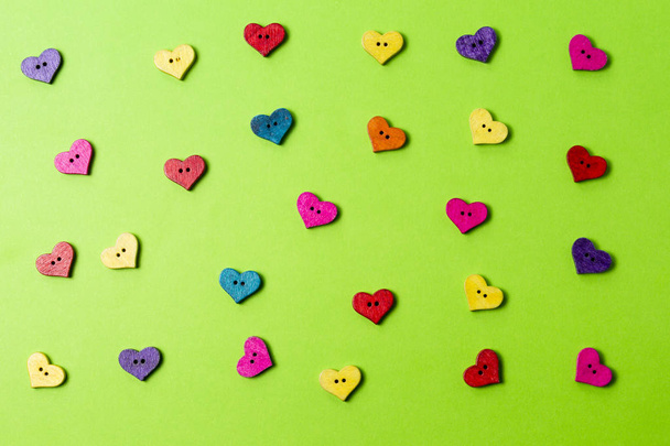 Botões coloridos em forma de coração de madeira no fundo verde
 - Foto, Imagem