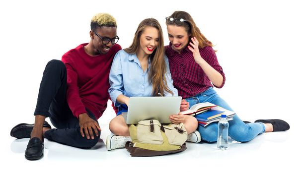 Trois étudiants heureux assis avec des livres, ordinateur portable et sacs
 - Photo, image