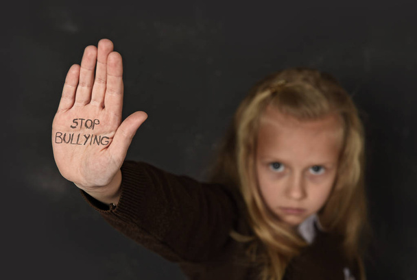 cute schoolgirl scared sad asking for help showing hands with stop bullying text written on her palm - Photo, Image