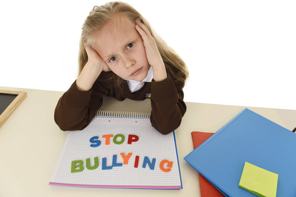 depressed young schoolgirl with stop bullying text on notebook helpless and scared as victim of bullying - Photo, Image