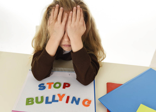 depressed young schoolgirl with stop bullying text on notebook helpless and scared as victim of bullying - Photo, Image