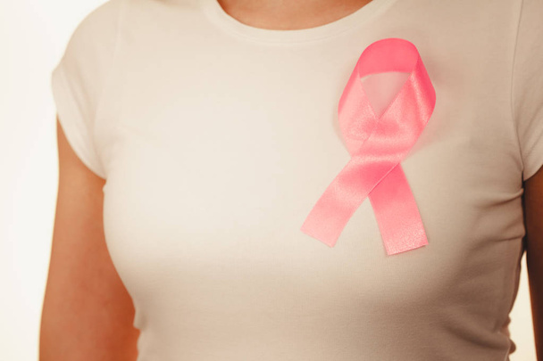 Closeup pink cancer ribbon on woman chest  - Fotografie, Obrázek