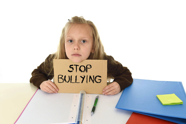  schoolgirl scared in stress holding paper with text stop bullying desperate asking for help - Photo, Image