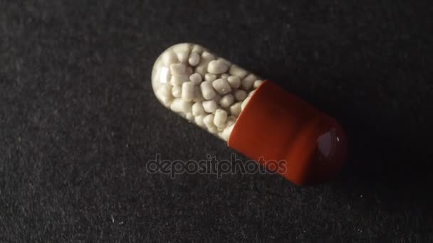 Makro lövés a barna és fehér tabletta kapszula forgó fekete háttér. - Felvétel, videó