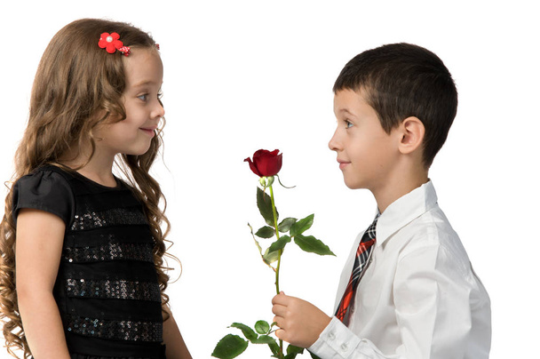 小さな男の子は、ガール フレンドに赤いバラを与えます。間の関係  - 写真・画像