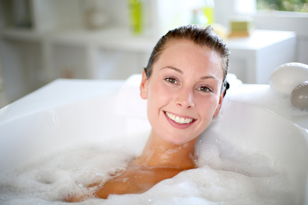 Smiling woman enjoying taking a bath - Foto, afbeelding