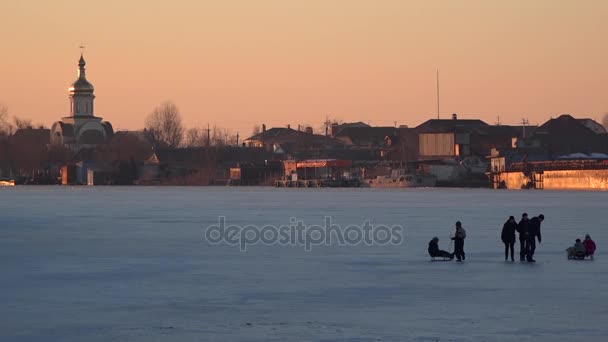 Children walking on the frozen river. The temple in the background, in the sun. - Footage, Video