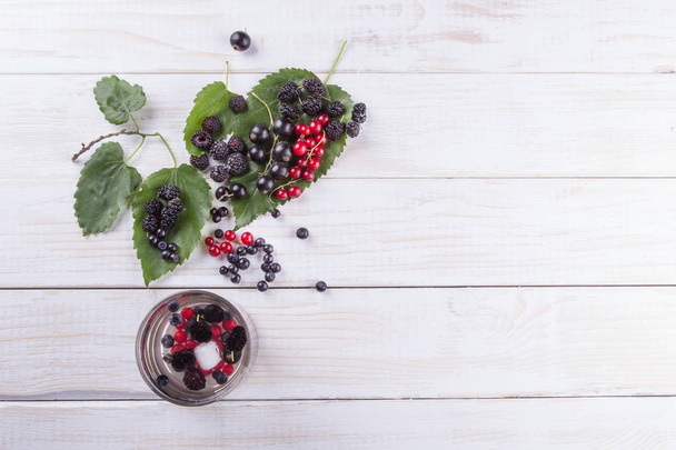 Mulberry berries, blackberries and currants on a white wooden table. The flat composition - Photo, Image