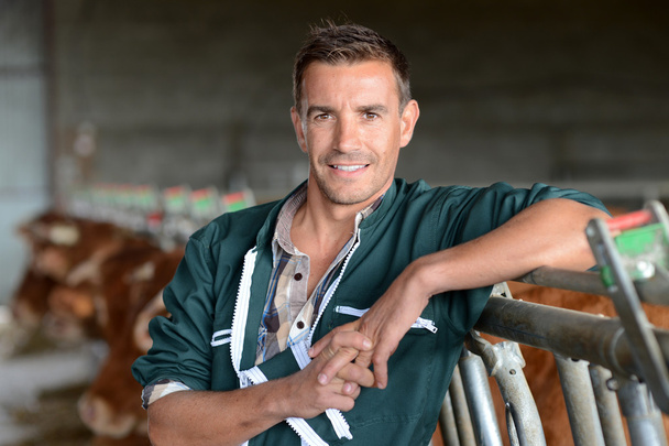 Portrait of smiling herdsman standing in barn - Foto, imagen