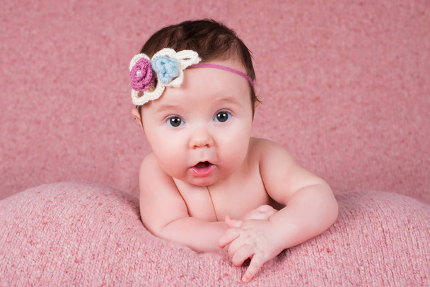 Newborn girl portrait with knitted bandage in the form of a flower. - Foto, imagen