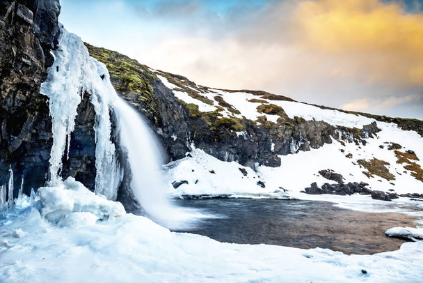 An icy waterfall during sunrise in Iceland - Fotó, kép