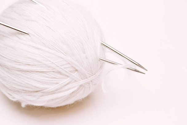 bola de hilo de lana blanca con agujas de punto sobre fondo blanco
 - Foto, Imagen