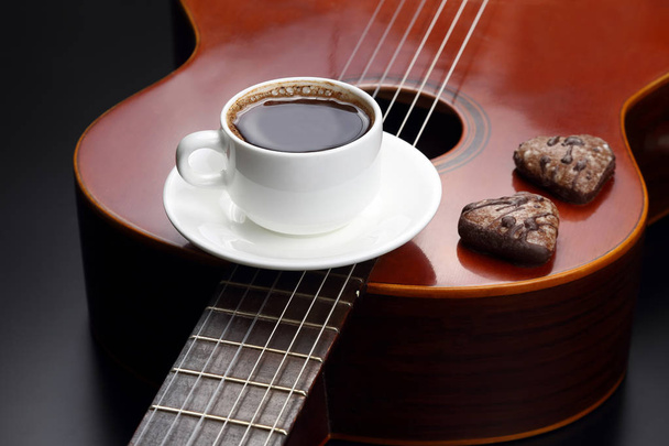 white cup with black coffee and cookies lying on the acoustic gu - Photo, Image