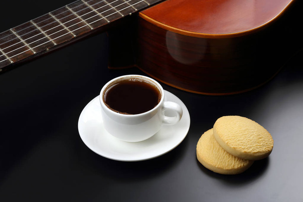 белая чашка с кофе и печеньем на фоне акустической гитары - Фото, изображение