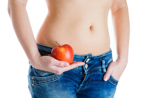 Vientre femenino. Manos de mujer sosteniendo manzana roja. FIV, embarazo, concepto de dieta
. - Foto, Imagen