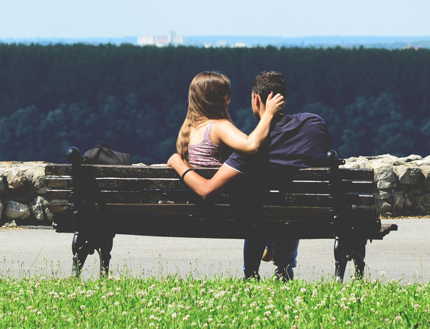 Back view of affectionate couple sitting on the bench - Foto, Imagen