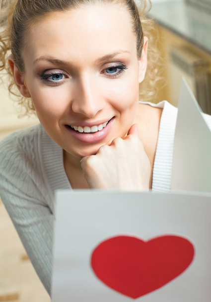 Cheerful smiling woman, reading valentine card - Fotoğraf, Görsel