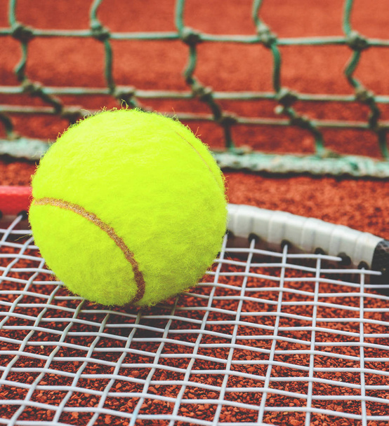Tennis racket with ball on it clay on clay court  - Foto, imagen