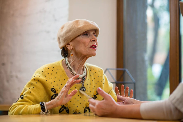 Ηλικιωμένη γυναίκα, μιλώντας στο τραπέζι. - Φωτογραφία, εικόνα