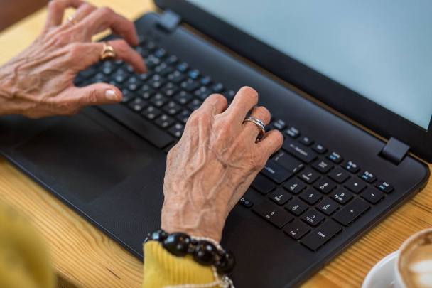 Old womans hands and laptop. - 写真・画像