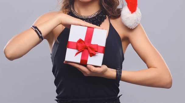 Young happy woman in santa hat holding christmas gift - Foto, imagen