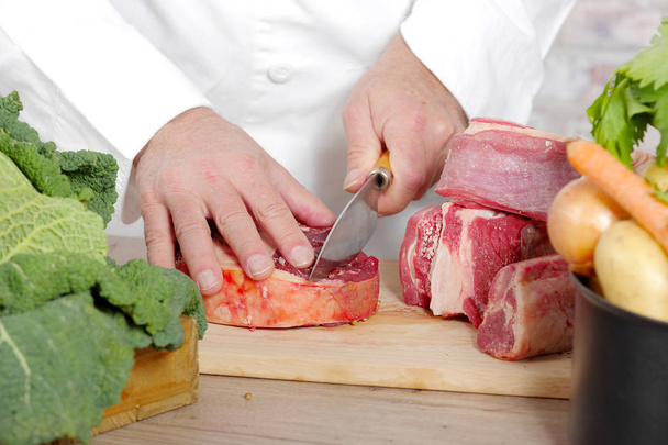 Шеф режет мясо на деревянной доске
 - Фото, изображение