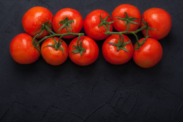 Red fresh organic tomatoes on black concrete background - Zdjęcie, obraz