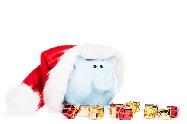 Piggy bank wearing santas hat with tiny christmas presents - Zdjęcie, obraz