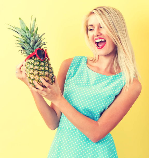 Happy young woman holding a pineapple - Foto, Bild