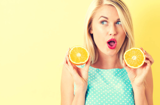 Happy young woman holding oranges halves  - Фото, изображение