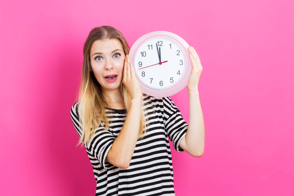 Woman holding clock showing nearly 12 - Foto, Imagen